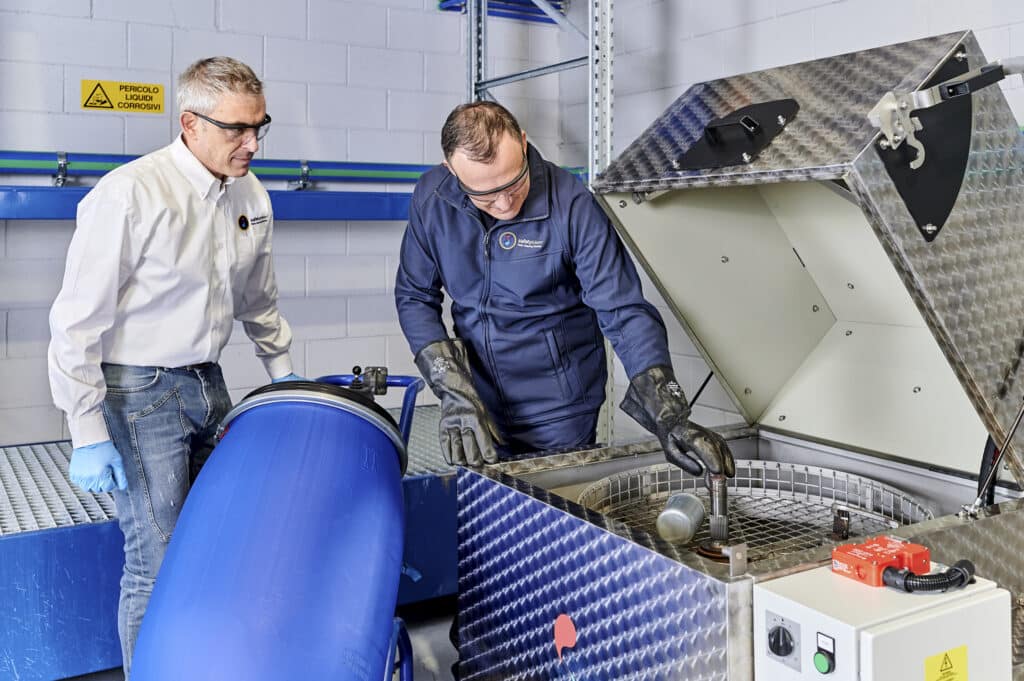 Dos técnicos especializados de Safetykleen realizan el mantenimiento y la recogida de residuos de la lavadora de piezas automática.